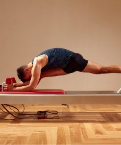 Homem a praticar pilates no equipamento reformer, demonstrando força, controlo e flexibilidade numa sessão de exercício focada no equilíbrio postural e bem-estar físico.