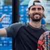 Jogador de padel sorridente com raquete na mão, em campo exterior.
